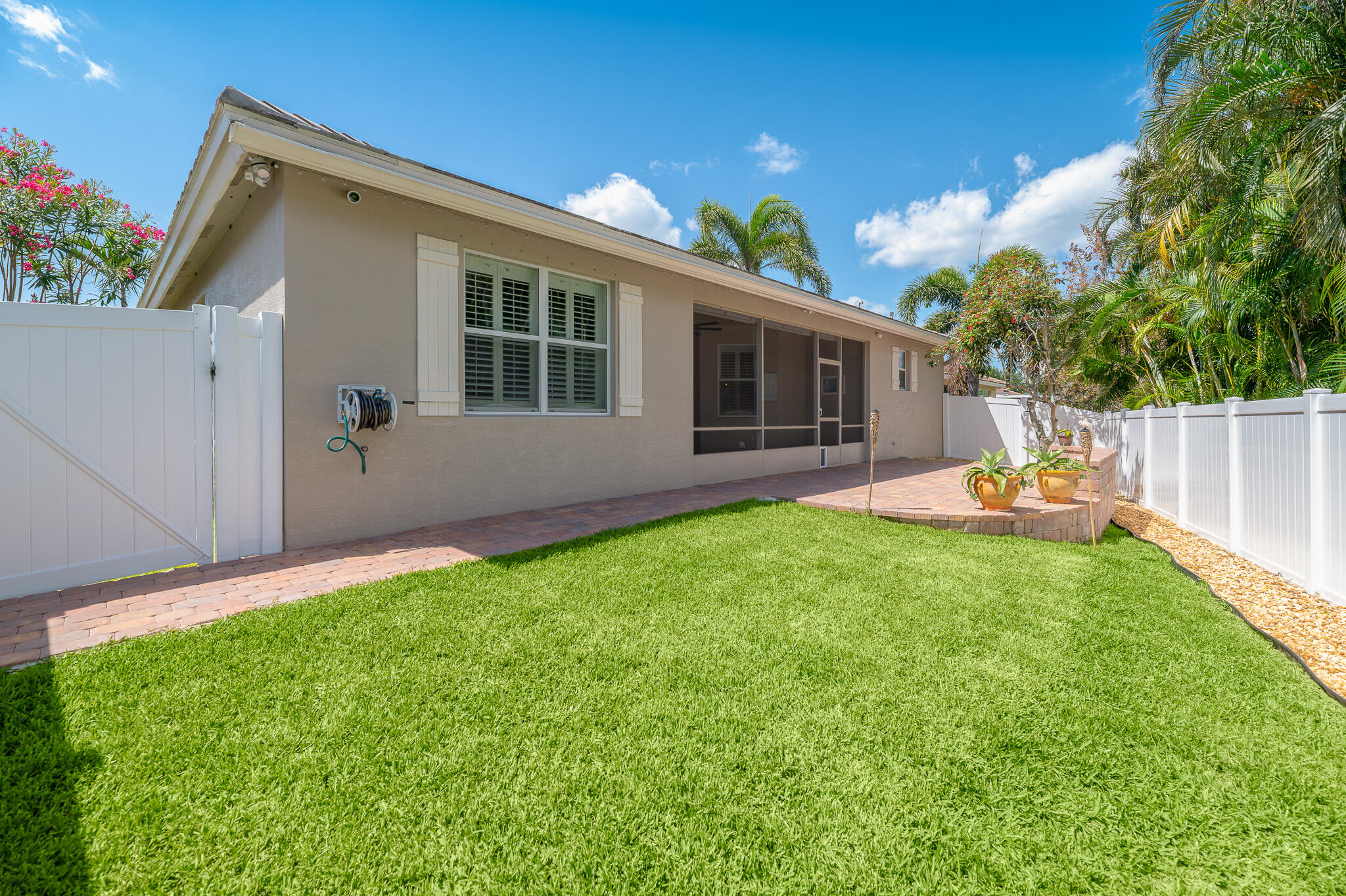 2187 Northwest Dalea Way Stuart, FL 34994 - Photo 28 of 41 a backyard of a house with table and chairs potted plants and large tree