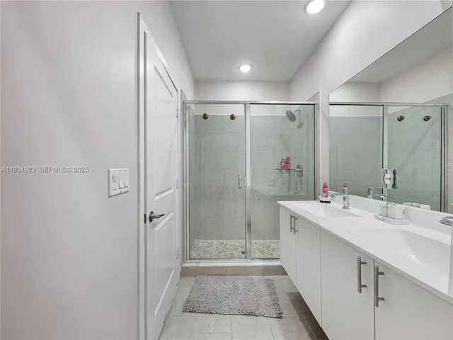 a bathroom with a shower sink vanity and mirror