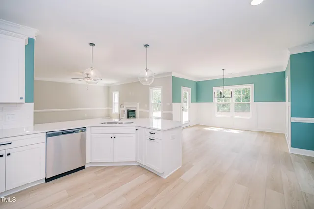a open kitchen with granite countertop a stove a sink and white cabinets with wooden floor next to windows