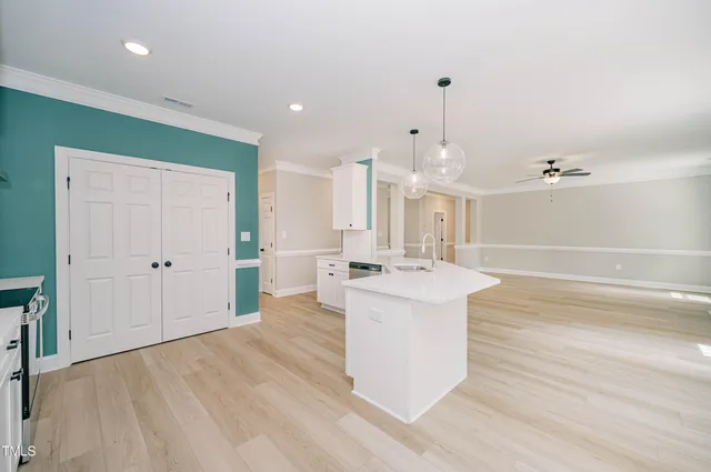 a large kitchen with a sink dishwasher a stove and a refrigerator with wooden floor