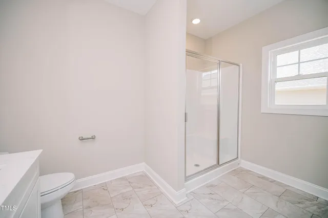 a bathroom with a granite countertop sink a toilet and a window