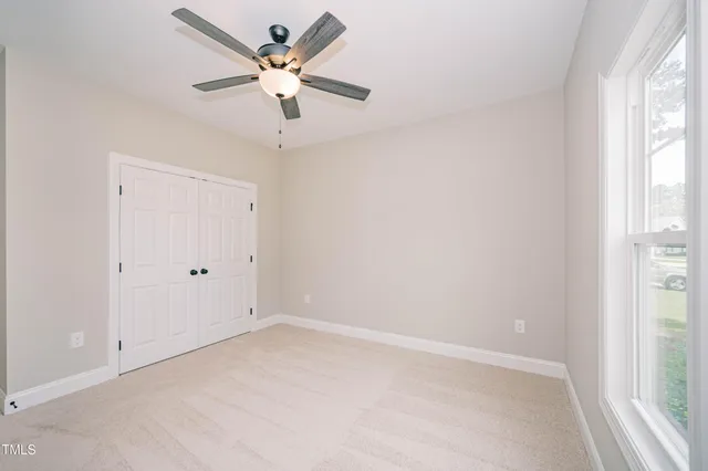 an empty room with a window and a fan