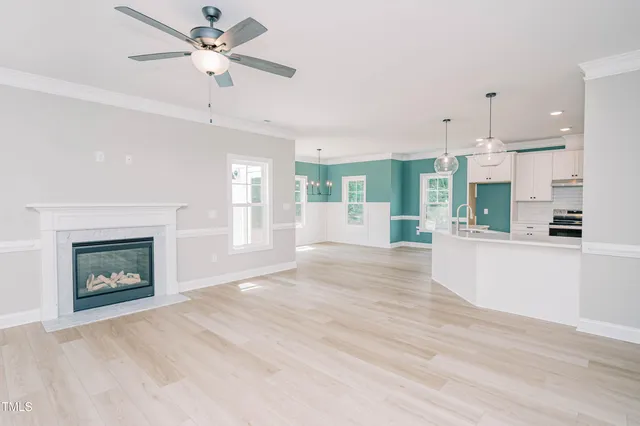 a view of an empty room with a kitchen and fireplace