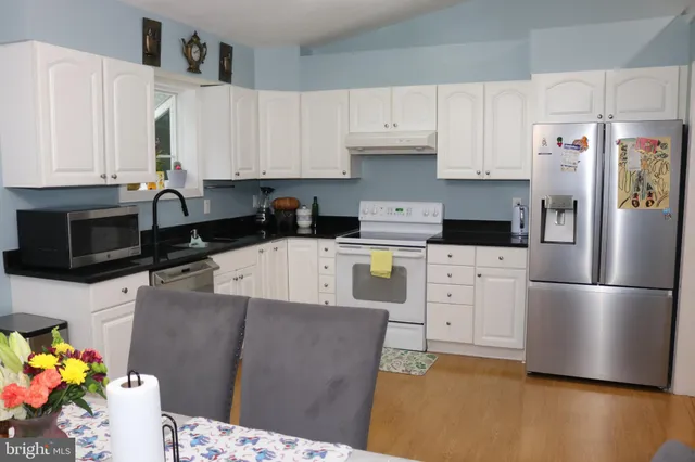 a kitchen with stainless steel appliances kitchen island granite countertop a refrigerator sink and white cabinets