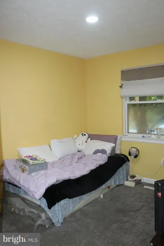 a bedroom with a bed and teddy bear on bed