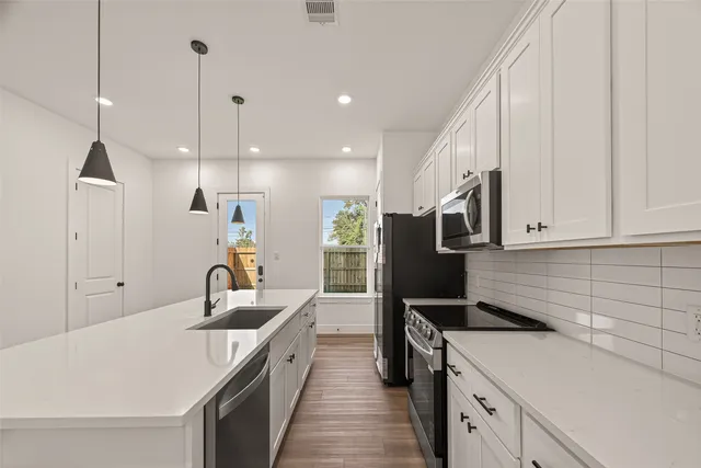 a kitchen with a sink a counter top space stainless steel appliances and cabinets