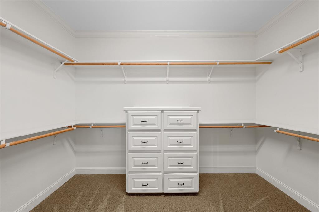 144 Ellis Farm Road Hewitt, TX 76643 - Photo 26 of 36 Walk-in closet featuring a built-in eight-drawer dresser, extensive shelving, multiple hanging rods, crown molding, and carpet flooring