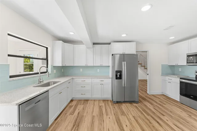 a kitchen with white cabinets and a window