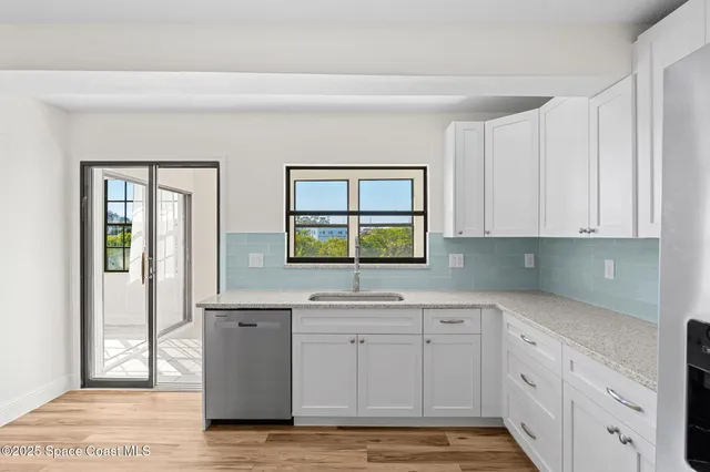 a kitchen with white cabinets and wooden floor