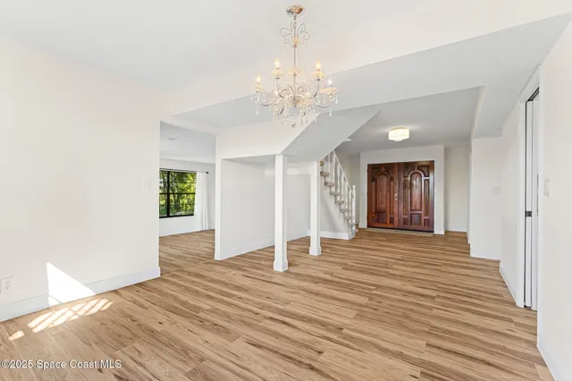 a view of an empty room with wooden floor and window