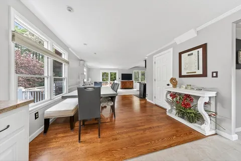 a living room with furniture and a dining table with wooden floor