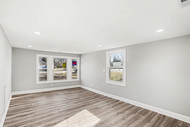 a view of an empty room with a window and wooden floor