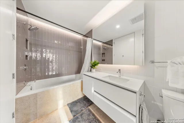 a bathroom with a granite countertop sink mirror and a bathtub