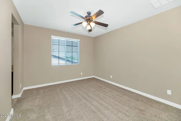 an empty room with a chandelier fan and windows
