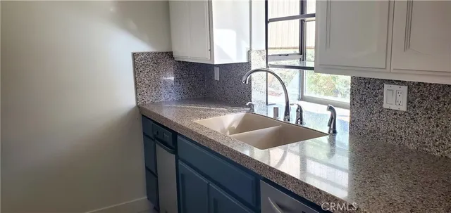 a kitchen with granite countertop a sink a window and cabinets