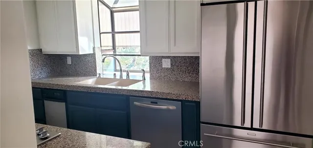 a kitchen with granite countertop white cabinets and black appliances