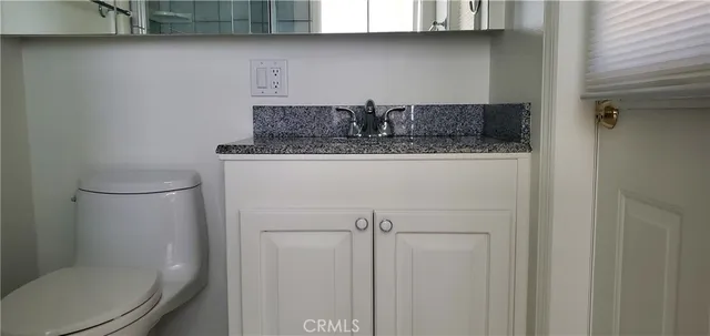 a bathroom with a granite countertop toilet and a sink