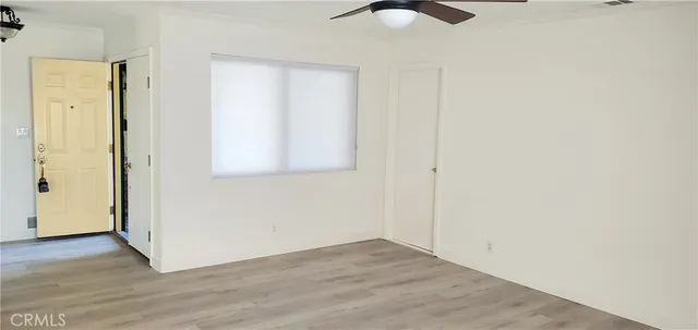 an empty room with wooden floor closet and windows