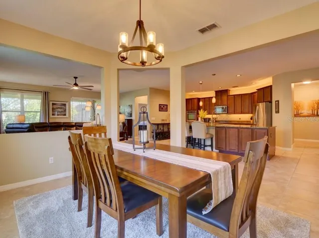 a dining room with furniture a chandelier and kitchen view