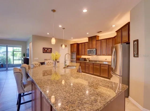 a large kitchen with kitchen island a large counter top stainless steel appliances and cabinets