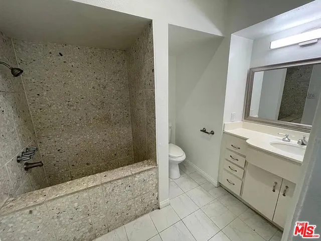 a bathroom with a granite countertop sink toilet and shower