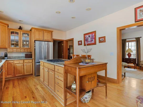 a open kitchen with stainless steel appliances granite countertop a stove top oven a sink a dining table and chairs with wooden floor