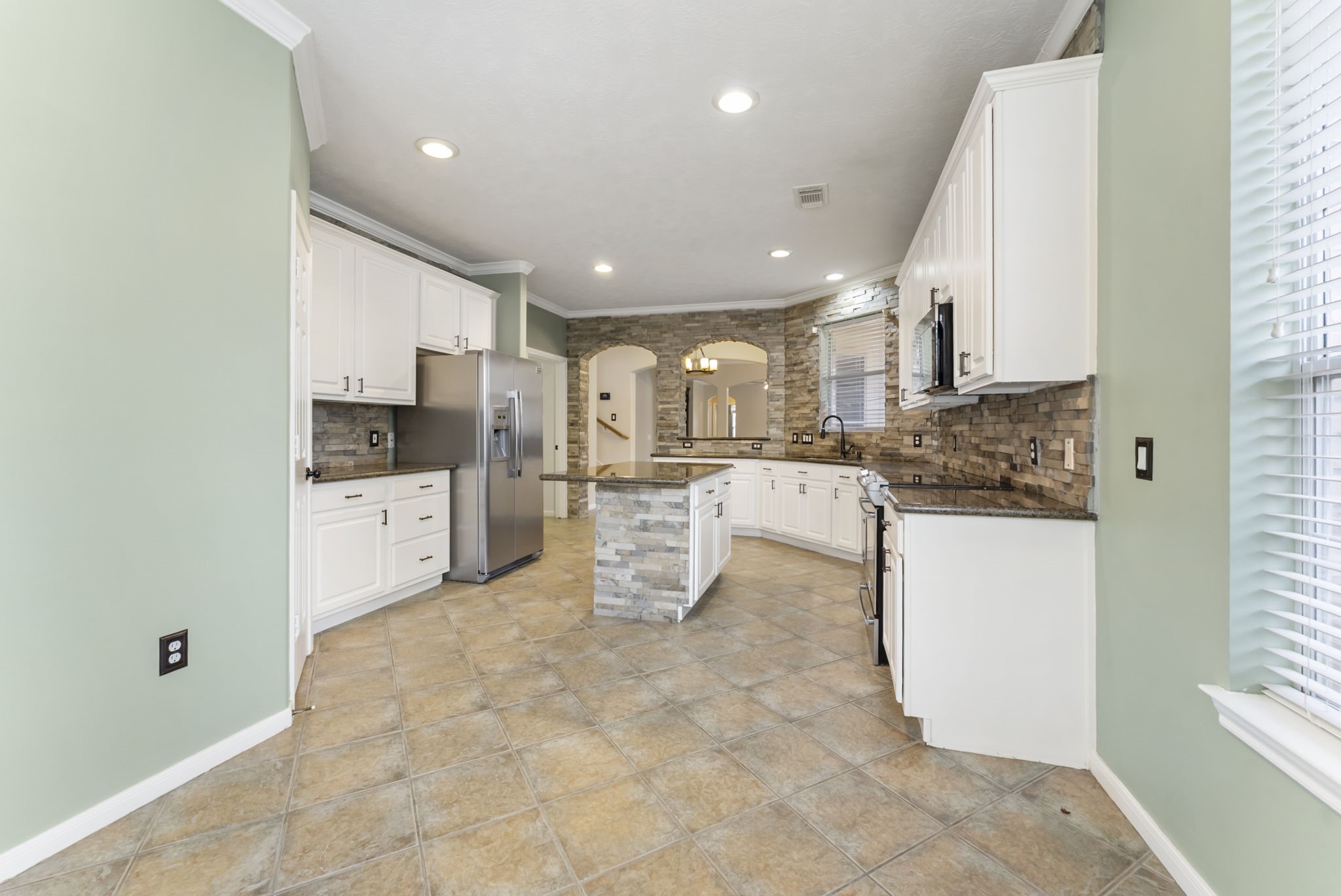 11 South Bendrook Loop Conroe, TX 77384 - Photo 7 of 27 a kitchen with stainless steel appliances kitchen island granite countertop a sink and cabinets