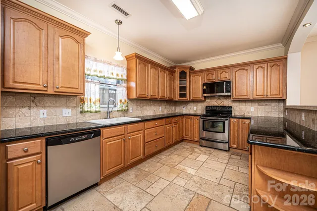 a kitchen with stainless steel appliances granite countertop a stove sink microwave and window