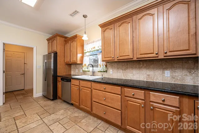 a kitchen with granite countertop a refrigerator and cabinets