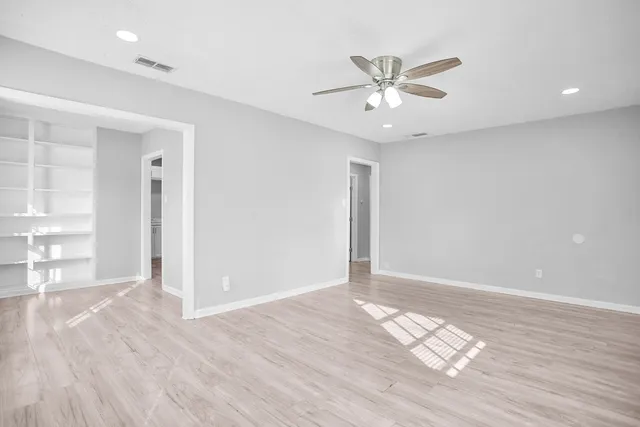 a view of a big room with windows and chandelier fan