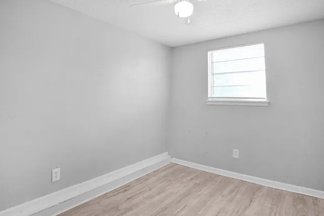 an empty room with wooden floor and windows