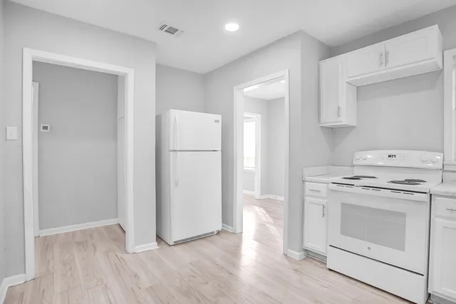 a kitchen with white cabinets appliances and a window