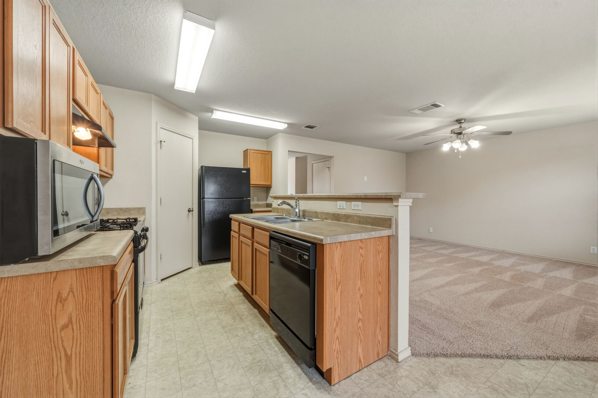 4528 Best Way Austin, TX 78725 - Photo 15 of 40 Kitchen with light flooring, black appliances, a ceiling fan, light countertops, and light carpet