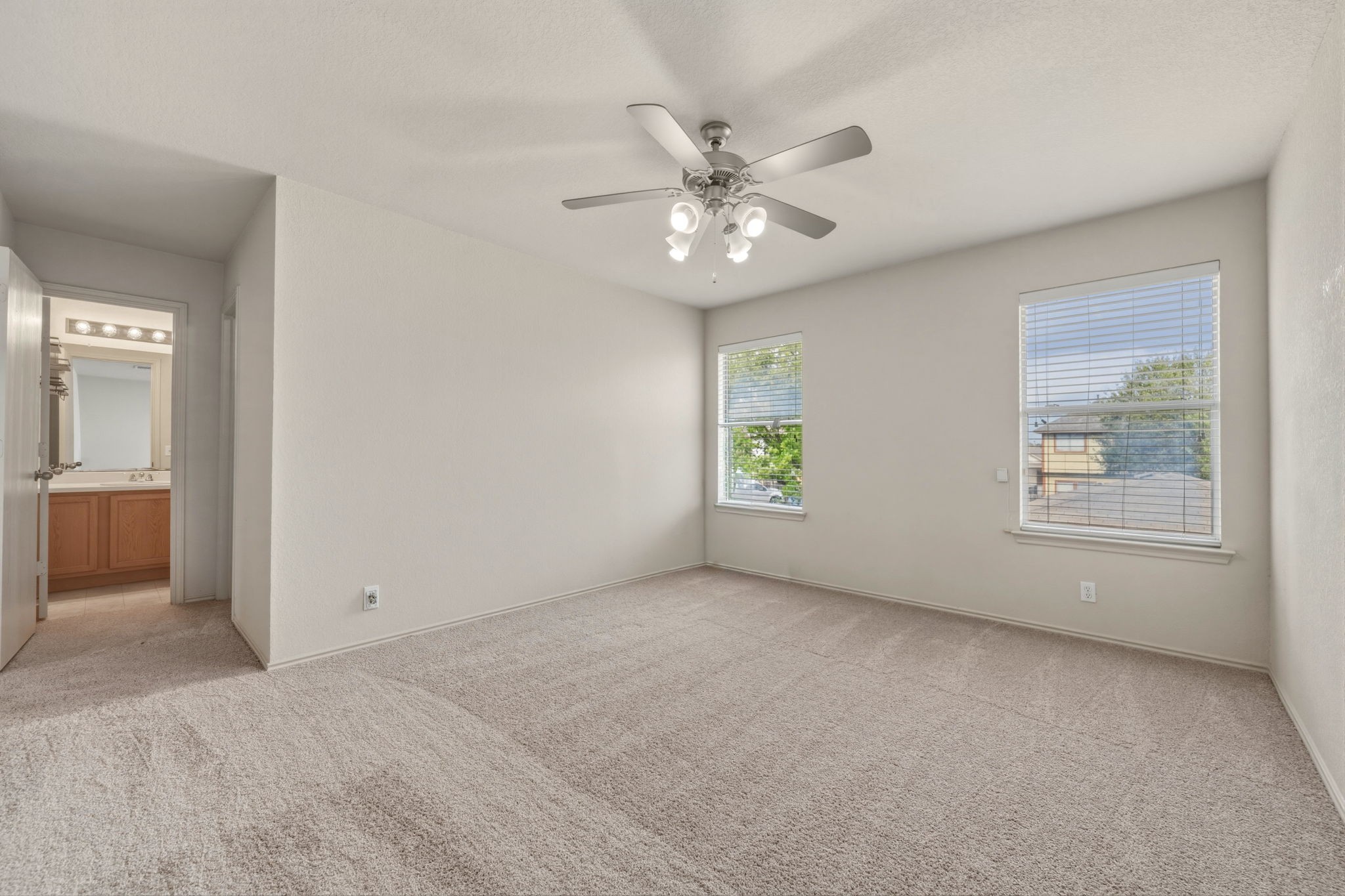 4528 Best Way Austin, TX 78725 - Photo 29 of 40 Unfurnished bedroom with light carpet, connected bathroom, and a ceiling fan