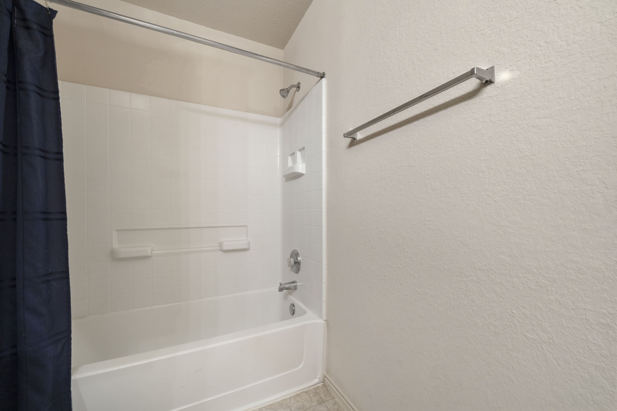 4528 Best Way Austin, TX 78725 - Photo 34 of 40 Full bath featuring a textured wall and shower / tub combo with curtain