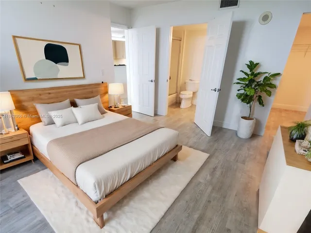a bedroom with a large bed and a potted plant