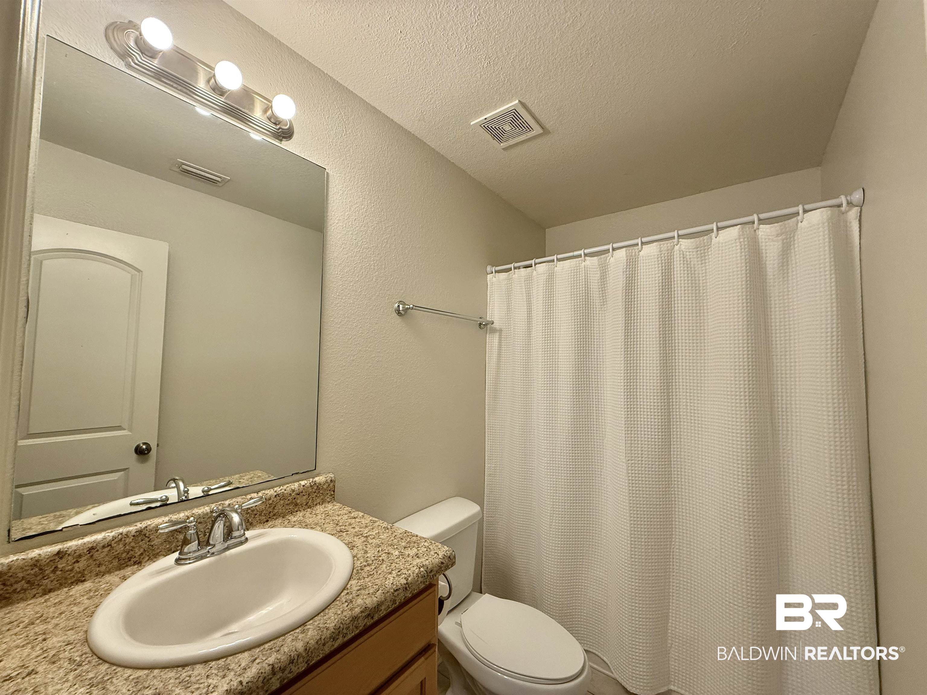 125 Bethea Road Brewton, AL 36426 - Photo 10 of 14 Bathroom with vanity, curtained shower, a textured ceiling, and a textured wall