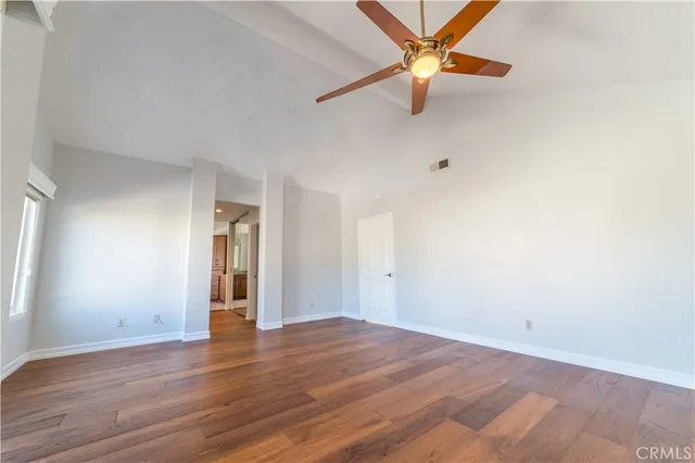 an empty room with wooden floor and a ceiling fan