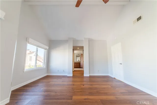 an empty room with wooden floor and windows