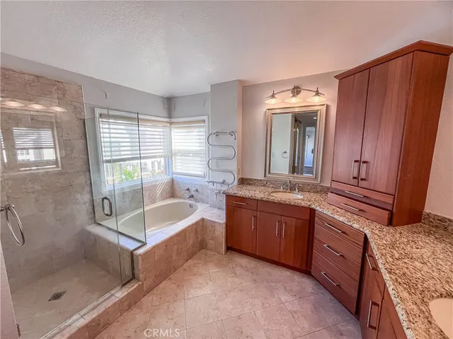 a bathroom with a granite countertop tub sink and mirror
