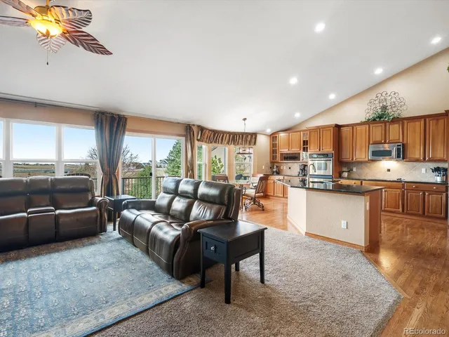 a living room with stainless steel appliances granite countertop furniture a couch a large window and kitchen view