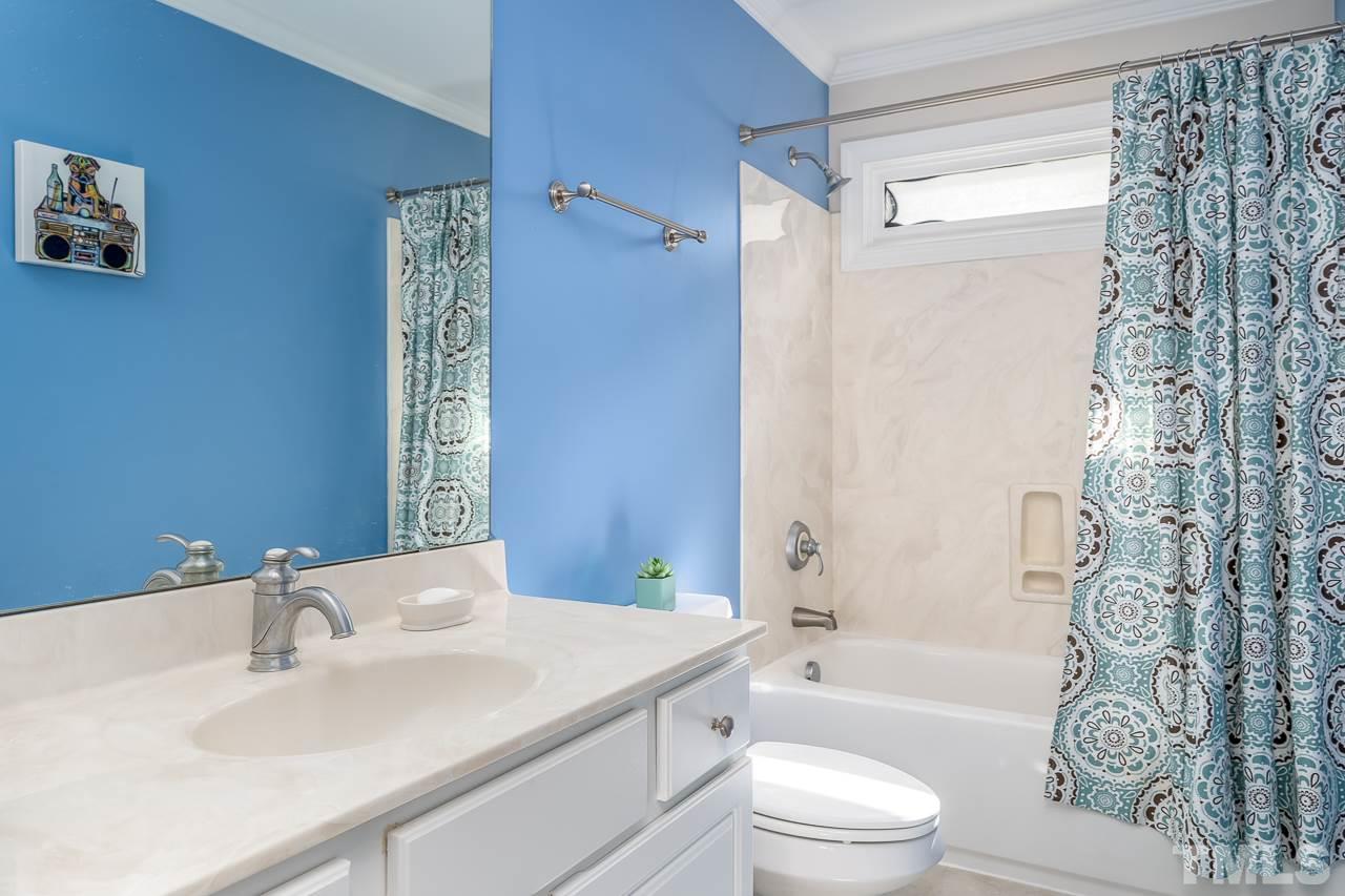 535 Pace Street Raleigh, NC 27604 - Photo 19 of 25 a bathroom with a sink a toilet a mirror a bathtub and shower