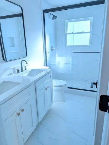 a bathroom with a granite countertop sink toilet and shower