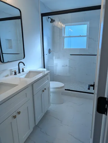 a bathroom with a double vanity sink mirror and toilet