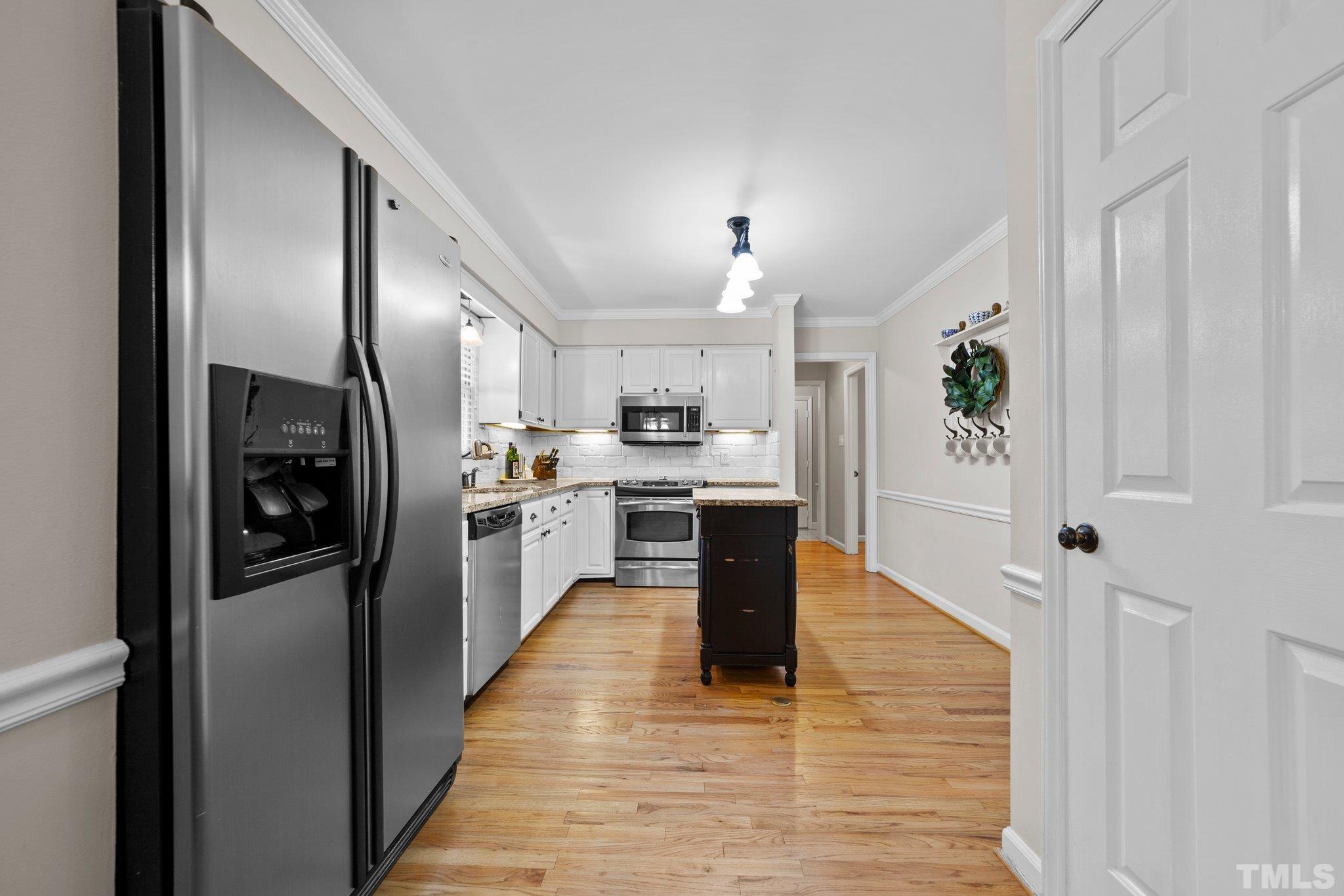 8709 Langtree Lane Raleigh, NC 27613 - Photo 15 of 49 a large kitchen with stainless steel appliances kitchen island a refrigerator sink and cabinets