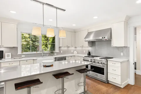 a kitchen with a stove a sink a window and cabinets