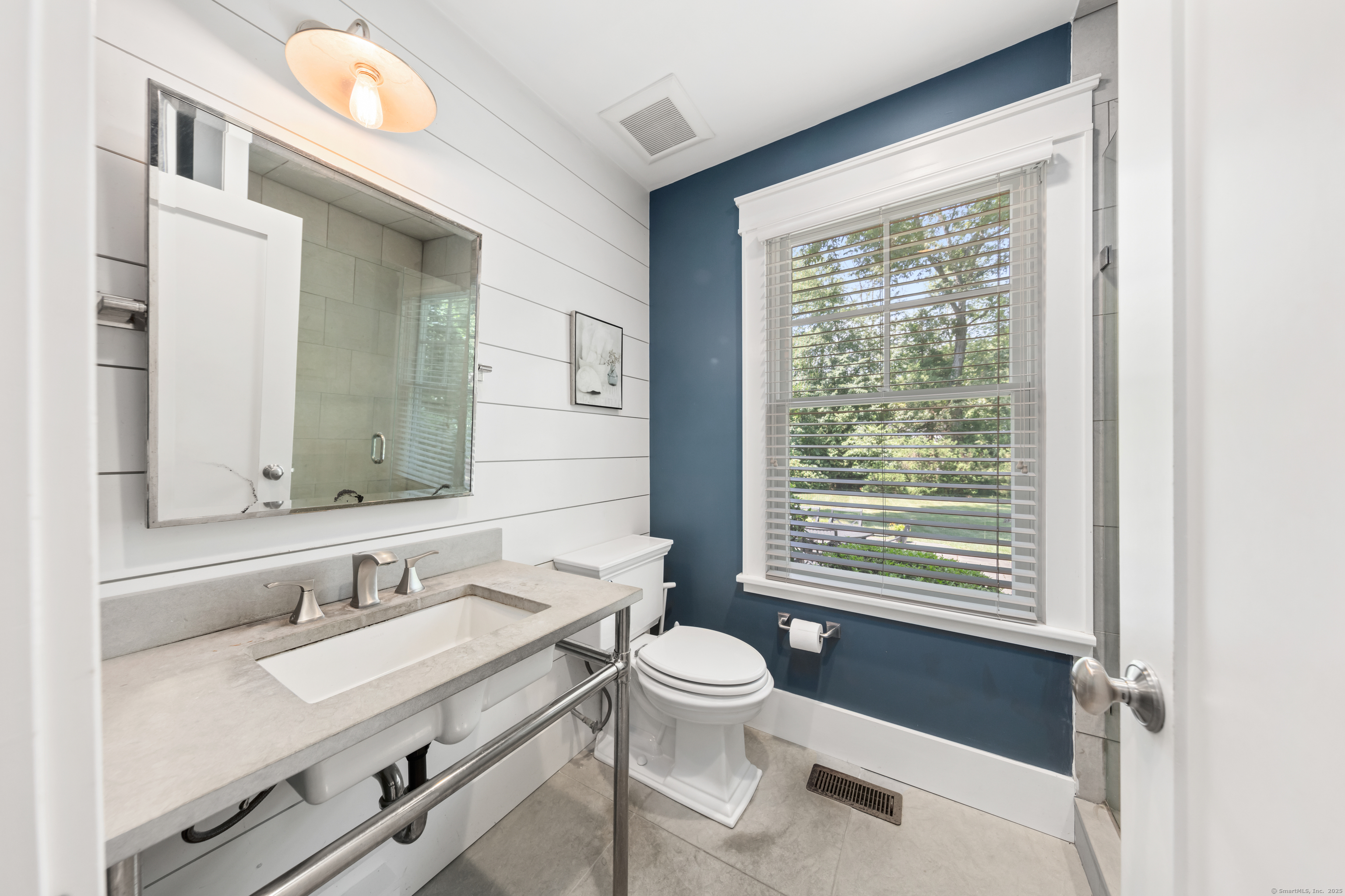 358 Hoyt Street Darien, CT 06820 - Photo 21 of 40 a bathroom with a granite countertop sink toilet a large mirror and a window