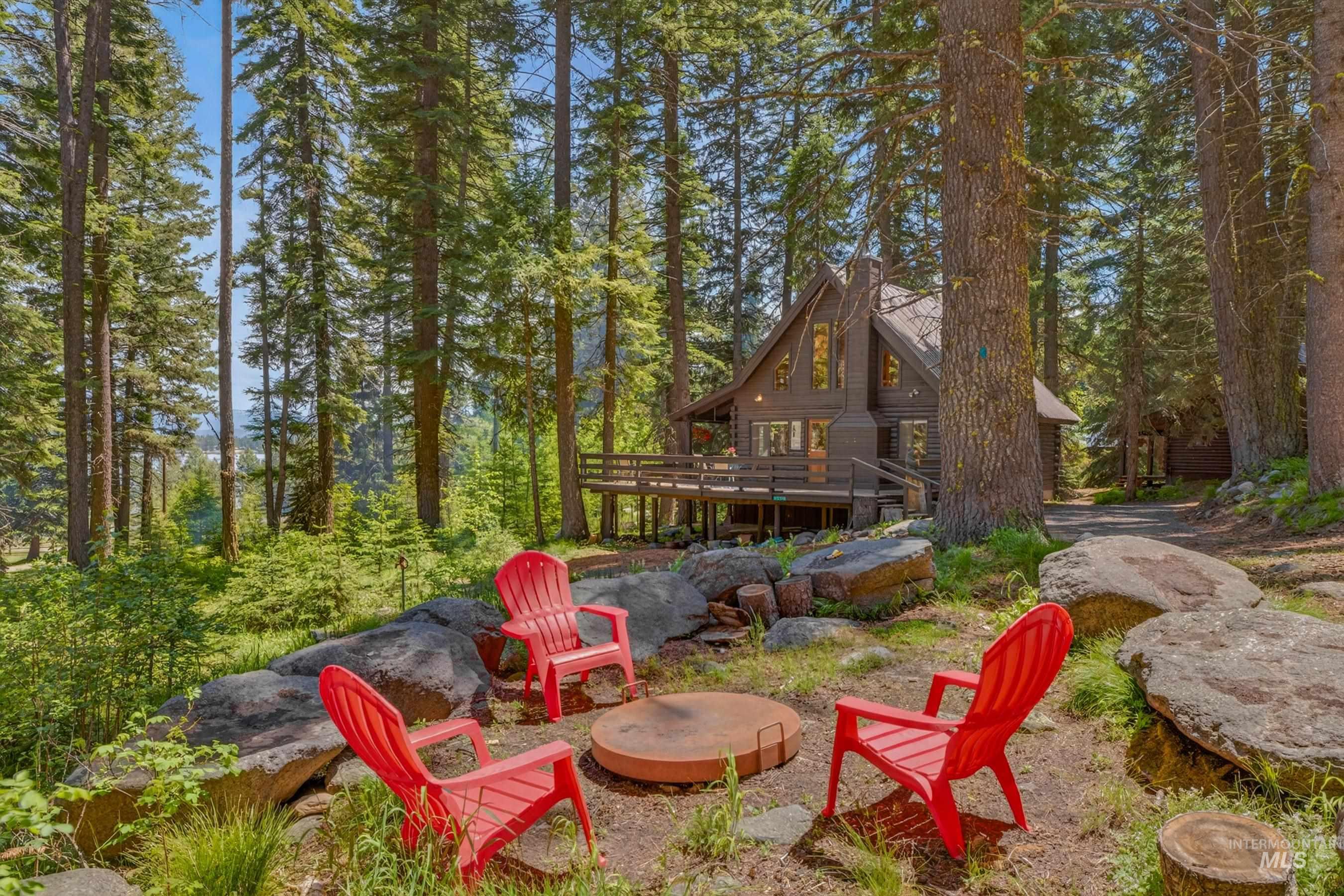 2339 West Mountain Road Donnelly, ID 83615 - Photo 32 of 37 Rustic cabin exterior featuring a multi-level deck, prominent chimney, and a gravel driveway