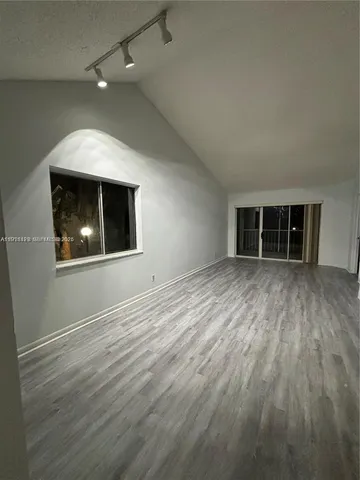 an empty room with wooden floor cabinet and windows