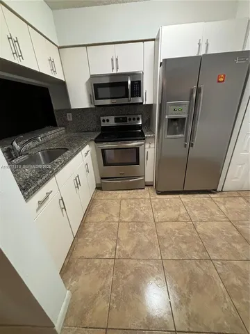 a kitchen with stainless steel appliances a sink a stove a microwave and cabinets